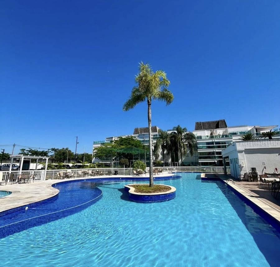 Piscina do Barra Village House Life com palmeira em ilha central, sob céu azul